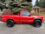 1997 GMC Sierra 1500 SL 4x4 in red with black wheels, showcasing its classic style and excellent condition.