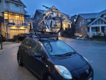 2007 Toyota Yaris hatchback parked with a bicycle on the roof rack in a suburban neighborhood