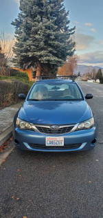 2008 Subaru Impreza in good condition with roof racks parked on the street, showcasing its clean exterior and snow tires.