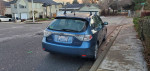 2008 Subaru Impreza with snow tires and roof rack parked on a residential street