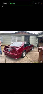 1990 Ford Mustang GT parked outside a house, showcasing its polished exterior and classic design.