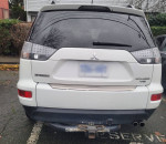 Rear view of a 2010 white Mitsubishi Outlander SUV with new winter tires and original rims.