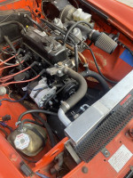 Engine compartment of a red 1980 MG convertible with performance upgrades and dual carburetors.