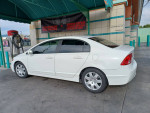 A white Honda Civic parked at a gas station, showcasing its good condition and clean exterior.