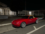 1994 Mazda MX-5 parked at night with yellow convertible top and aftermarket wheels