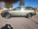2005 Subaru Outback with all-wheel drive, sunroof, and stylish wheels parked on the road.