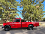 1993 Toyota T100 SR5 4WD with new all-terrain wheels, parked in a residential area with lush trees.