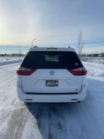 Back view of a well-maintained 2015 Toyota Sienna LE AWD, snow-covered background, showcasing its stable design.