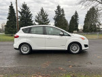 2014 Ford CMax Hybrid parked on street with green trees in background, showing sleek design and clean exterior.