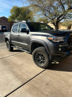 2018 Toyota Tacoma SR5 4WD in gray with a 2-inch lift, parked in a driveway under clear skies.