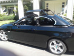 Black 2009 BMW 328i convertible with automated hard top, low mileage of 83,300 km, parked outdoors.