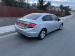 2014 Honda Civic sedan in silver, parked on the street, showcasing its sleek design and reliable build.