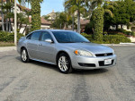 2013 Chevrolet Impala LTZ in silver parked, showcasing its good condition and stylish design with palm trees in the background.