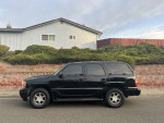 2006 GMC Yukon Denali AWD parked in front of a house, showcasing its sleek design and clean appearance.