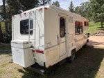 Rear view of a 1990 Toyota Sunrader motor home with LED lights and reinforced bumper in a natural setting
