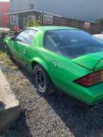 1988 Chevrolet Camaro in custom Slimer green paint, showcasing sporty design and rear profile on display.