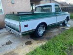 1972 GMC C10 short bed truck in green and white parked, showcasing its classic design and lower stance.