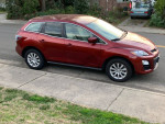 2012 Mazda CX-7 in red, parked on a residential street, showcasing its exterior design.