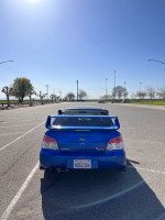 Rear view of a blue 2007 Subaru Impreza STI parked, showcasing its clean design and sporty spoiler.