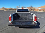 A rear view of a 2005 Dodge Dakota SLT Quad Cab V8 truck with a bed liner, parked in an empty lot.
