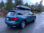 2017 Honda Pilot EX-L AWD with Yakima roof rack parked on a wet road, showcasing its sleek design.