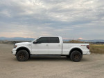 Side view of a 2014 Ford F-150 FX4 4WD in white, showcasing upgraded features and off-road wheels.