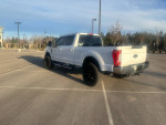 2017 Ford F350 Powerstroke 4x4 Lariat in parking lot with black wheels and flipback bed cover.