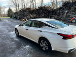 2019 Nissan Altima AWD parked with logs in the background, showcasing its sleek design and great condition.
